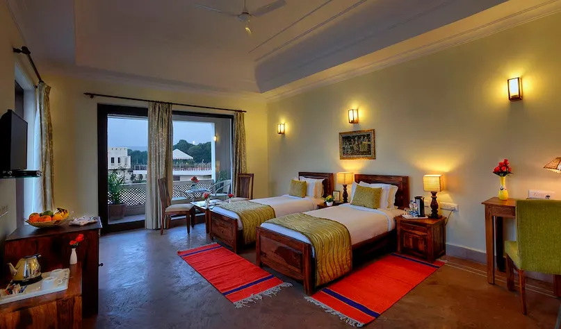 Deluxe room at Achrol Niwas Jaipur with spacious layout, seating area, and warm interior tones