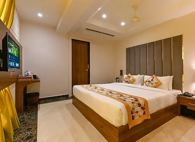 Deluxe room at Hotel Avalon Palms Agra showing larger layout, seating area, and window view