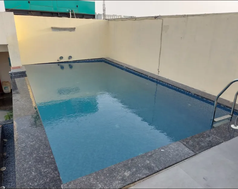 Swimming pool at Hotel Avalon Palms Agra with surrounding deck and outdoor seating