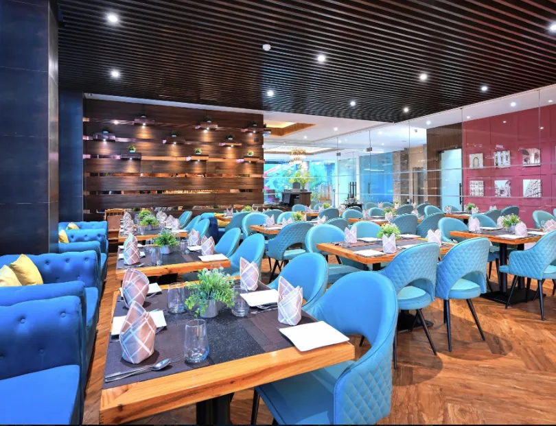 Restaurant at Golden Tulip Agra showing dining tables, chairs, lighting, and interior setup