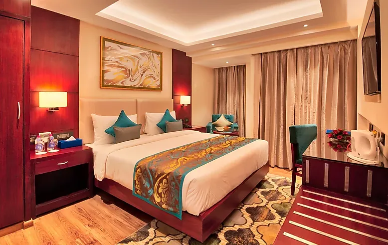 Standard room at Golden Tulip Essential Jaipur showing bed setup, lighting, and functional interior design