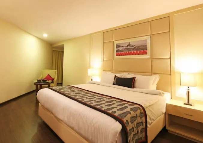 Deluxe room at Golden Tulip Jaipur with modern furnishings, seating area, and clean layout