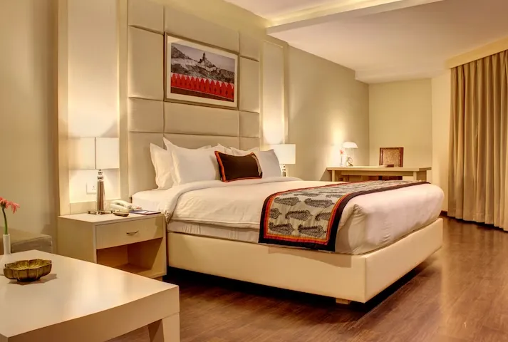 Deluxe room at Golden Tulip Jaipur with modern furnishings, seating area, and clean layout