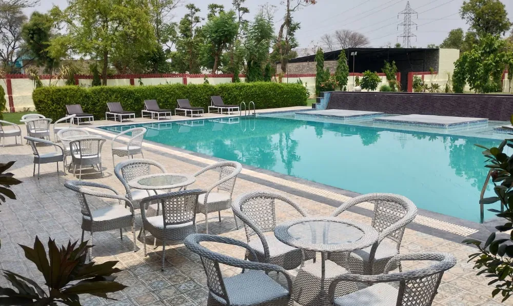 Swimming pool at Heena Heritage Resort Jaipur surrounded by deck space and seating