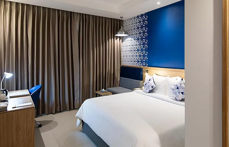 Deluxe room at Hometel Alambagh Lucknow showing added seating space and soft interior lighting