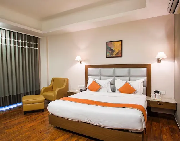 Deluxe room at Hotel Chirag Bikaner featuring larger layout, seating area, and neutral interiors