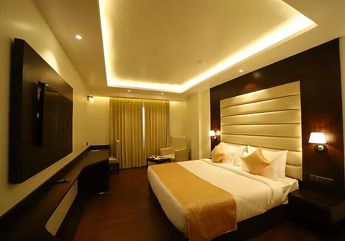 Deluxe room at Hotel DVIJ Inn Jaipur with neatly arranged bed and bedside furniture