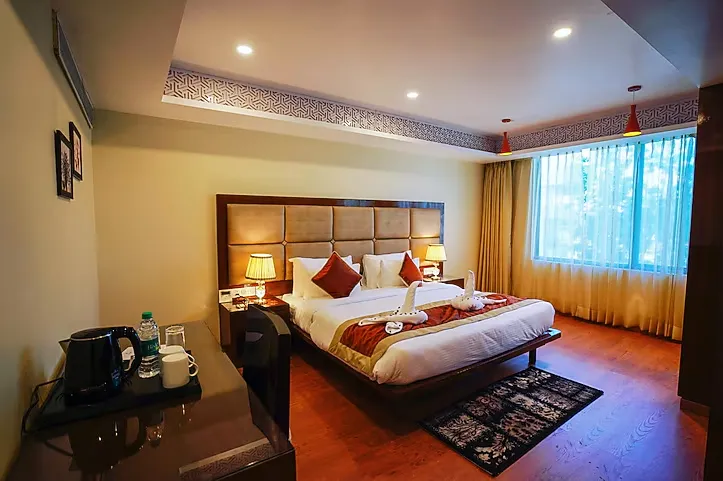 Deluxe room at Hotel Indo Prime Jaipur with twin or double bed and side tables