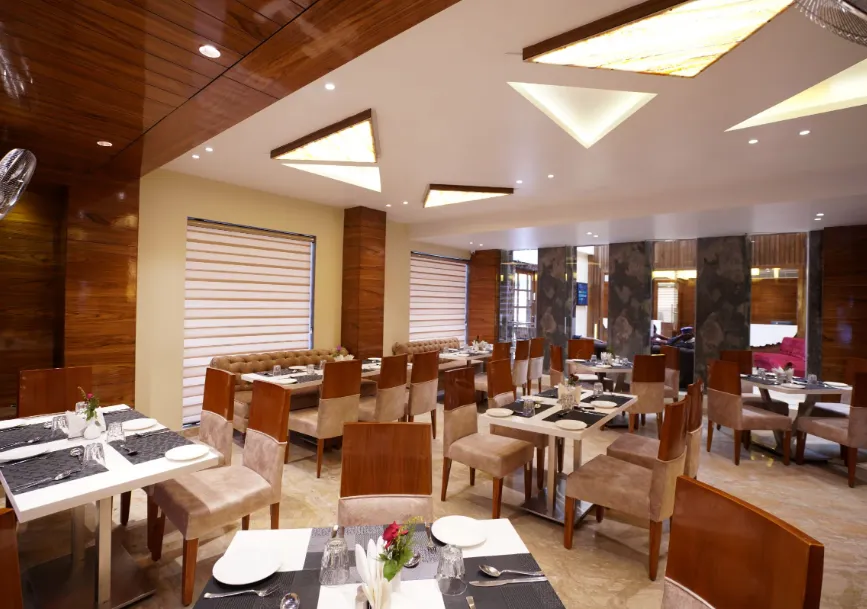 Restaurant at Hotel Indo Prime Jaipur featuring indoor dining tables and lighting