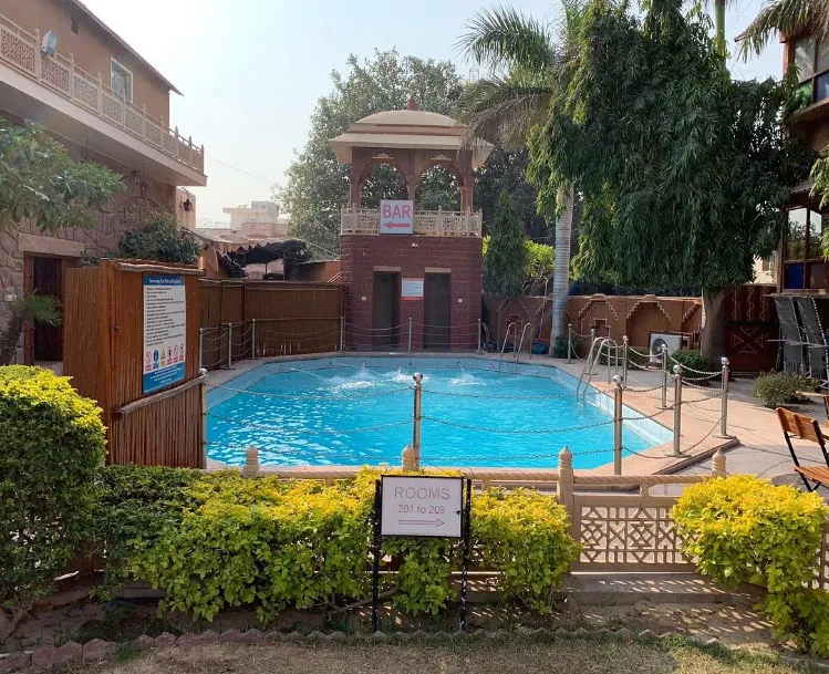 Outdoor swimming pool at Hotel Nirali Dhani Jodhpur surrounded by deck seating