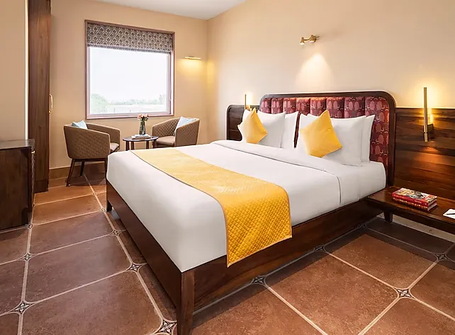 Designer room at Raasvan Vrindavan AM Hotel Kollection Vrindavan with minimalist décor and neatly arranged bedding