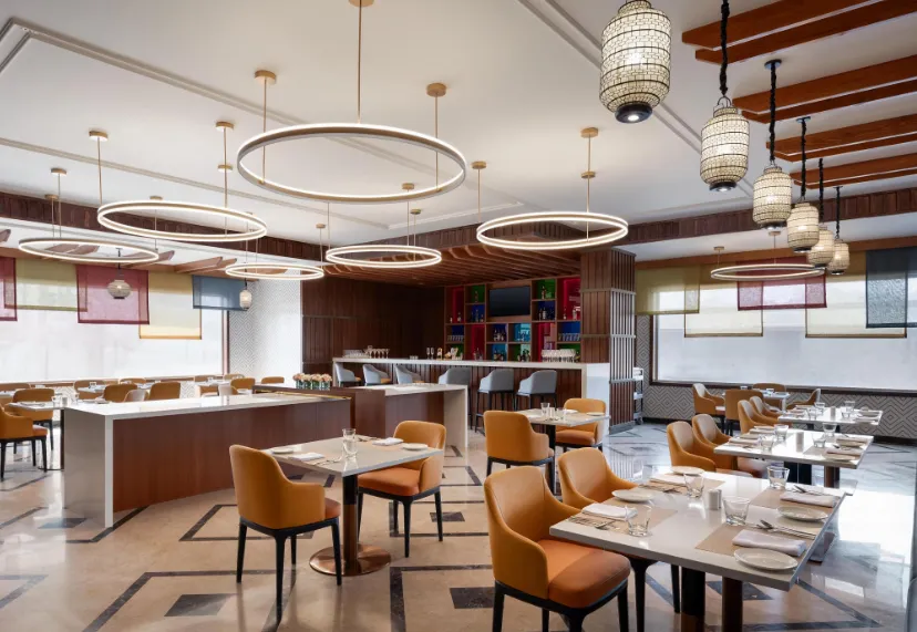 Restaurant at Ramada Encore By Wyndham Udaipur with dining tables, chairs, and warm interior lighting