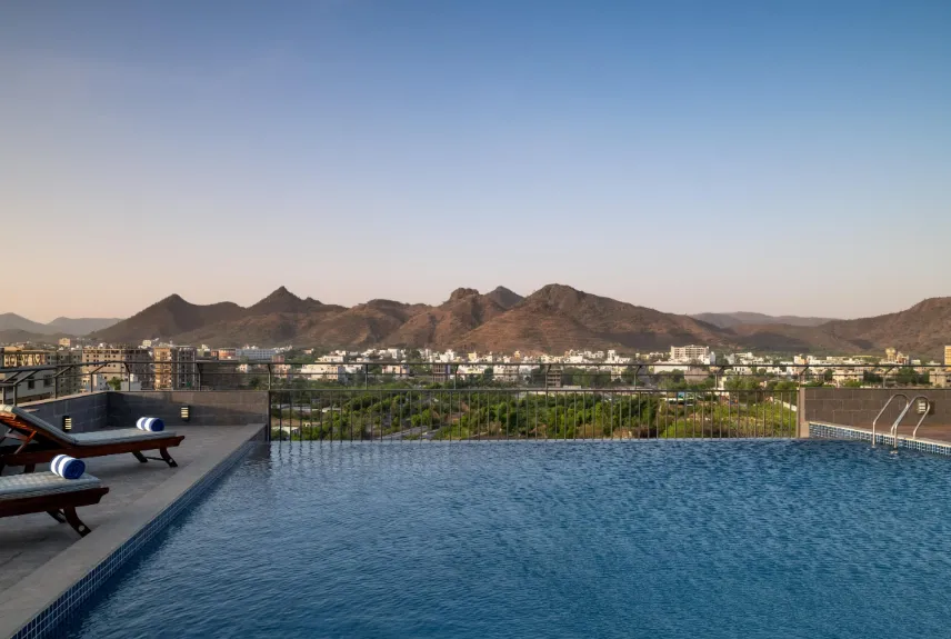 Swimming pool at Ramada Encore By Wyndham Udaipur with pool deck, clear water, and seating area