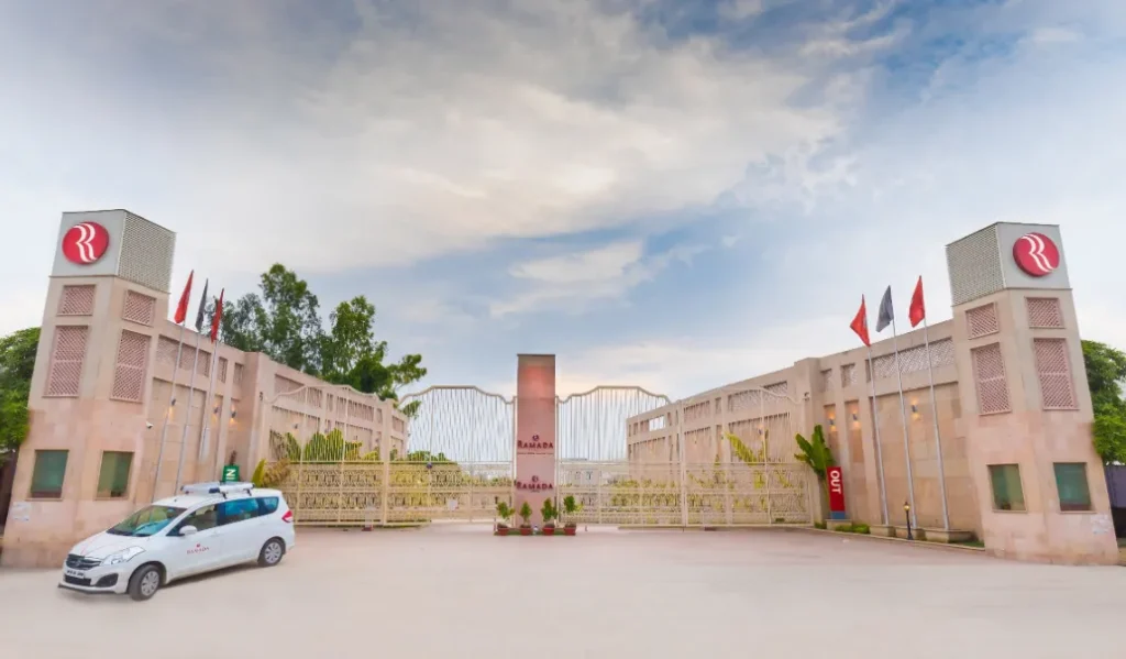 Hotel entrance of Ramada by Wyndham Lucknow Hotel and Convention Center with exterior façade and driveway