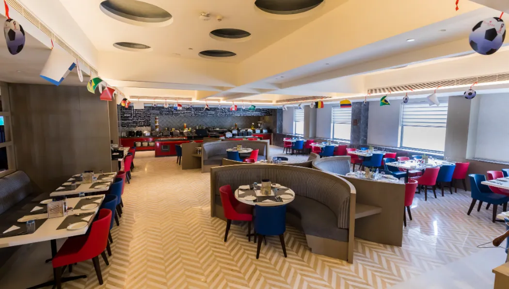 Restaurant at Ramada by Wyndham Lucknow Hotel and Convention Center displaying dining tables and interior design