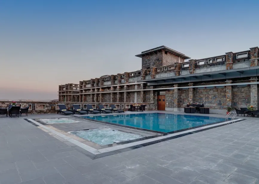Outdoor swimming pool at Ramada by Wyndham Udaipur Resort and Spa Udaipur with poolside deck and sun loungers