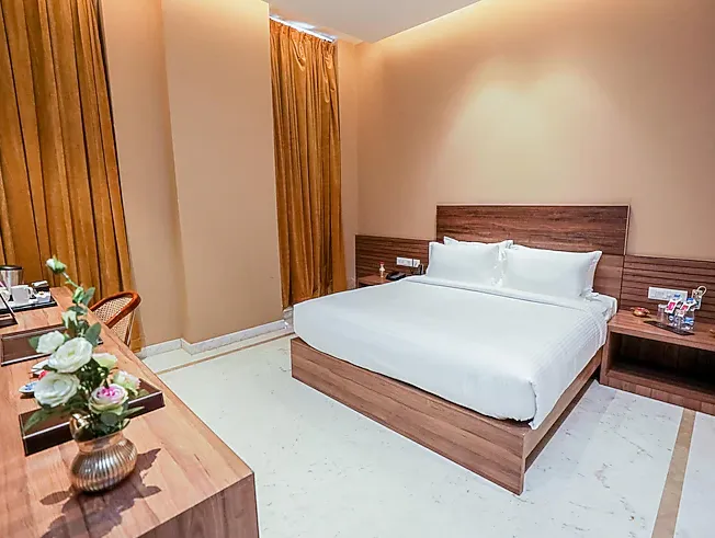 Standard room at Regenta Gulab Kothi Varanasi showing neatly arranged bed, side tables, and soft ambient lighting