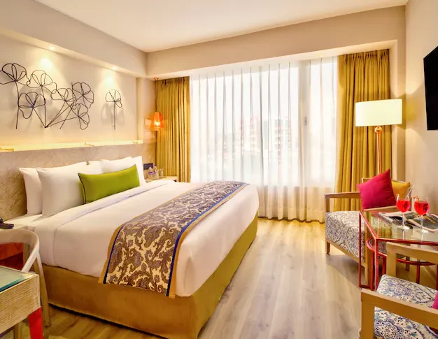 Deluxe room interior at Sarovar Premiere Jaipur with spacious bed, work desk, and neutral décor
