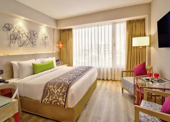Deluxe room interior at Sarovar Premiere Jaipur with spacious bed, work desk, and neutral décor