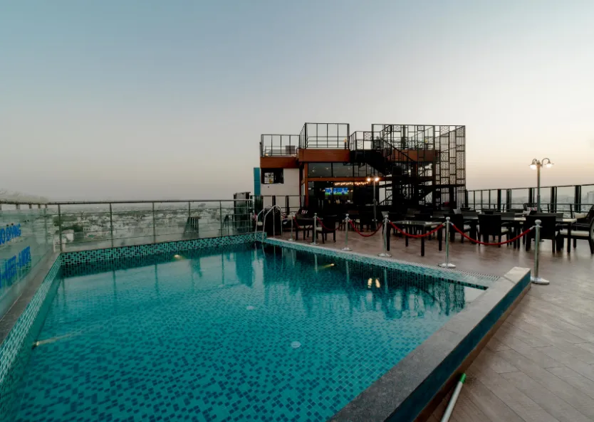 Swimming pool at Sarovar Portico Jaipur with poolside seating and open-air layout