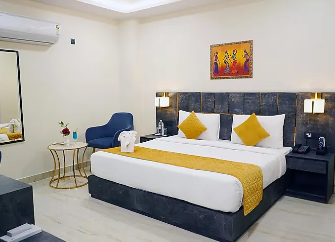 Premium room at Shrigo Hotels Banaras Varanasi with neatly arranged bed, side tables, and soft wall lighting