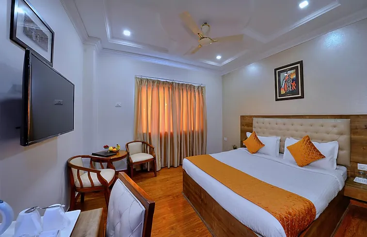 a room with a bed and a televisDeluxe room at Wingston A Treehouse Hotel Mathura featuring larger layout and seating spaceion