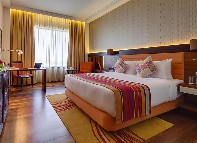 Deluxe room at Balaji Sarovar Premiere Solapur showing large bed and work desk