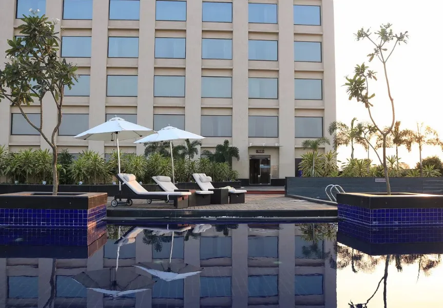 Swimming pool at Balaji Sarovar Premiere Solapur with poolside deck chairs
