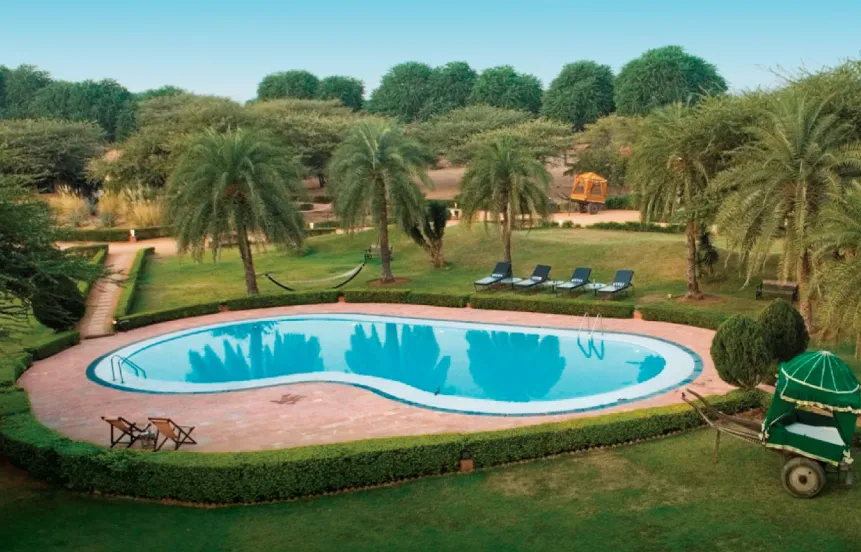 Outdoor swimming pool at Clarks Safari Pushkar with deck seating and clear water surface