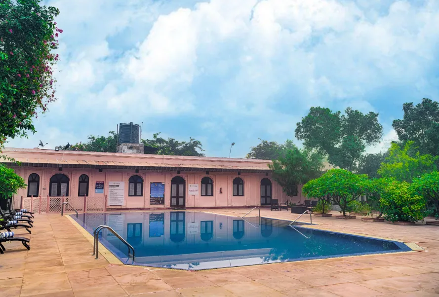 Outdoor swimming pool at Club Mahindra Bharatpur with clear water and deck chairs