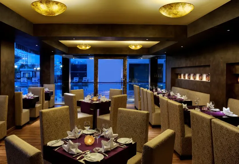 Restaurant at Golden Tulip BDI Club And Suites Bhiwadi with dining tables and interior
