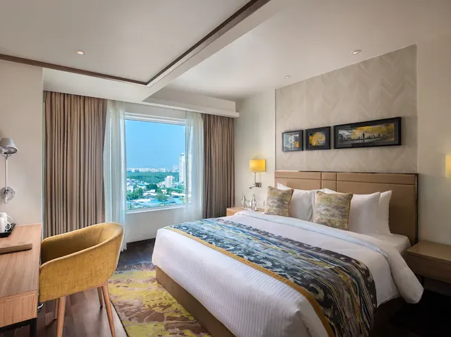 Deluxe room at Royal Hometel Suites Dahisar showing large bed, headboard and window