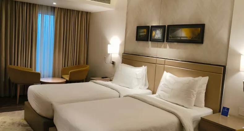 Deluxe room at Royal Hometel Suites Dahisar showing large bed, headboard and window