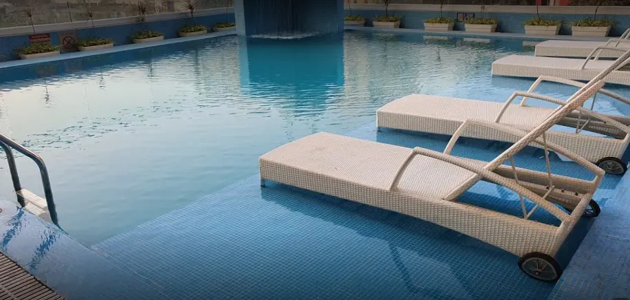 Swimming pool at Royal Hometel Suites Dahisar with clear water and poolside chairs