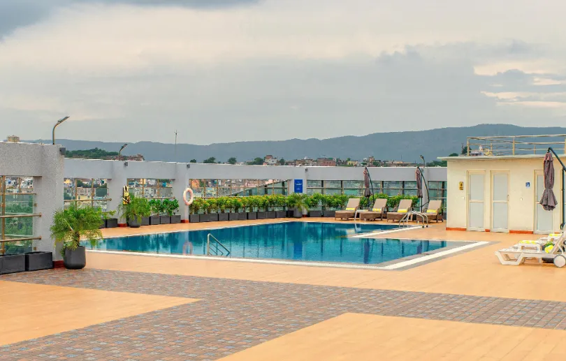 Outdoor swimming pool at Sarovar Portico Ajmer with pool deck chairs