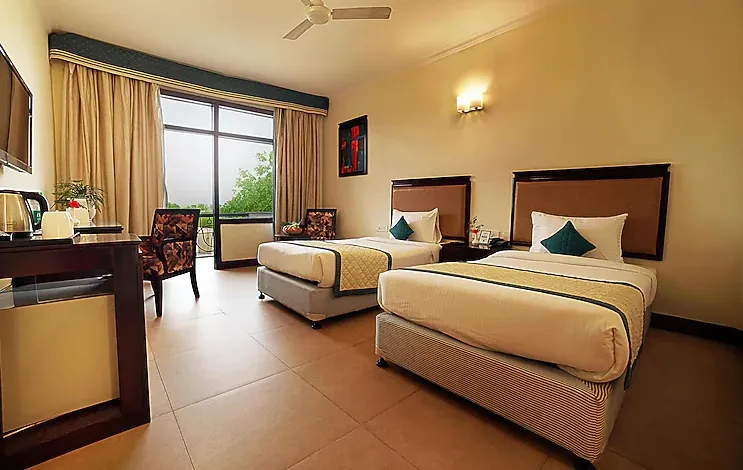 Deluxe room at TreeHouse Sunrise Resort & Caravan Park Neemrana with large bed and window view
