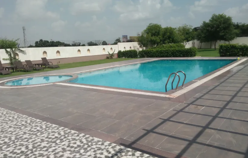 Outdoor swimming pool at TreeHouse Sunrise Resort & Caravan Park Neemrana with deck chairs