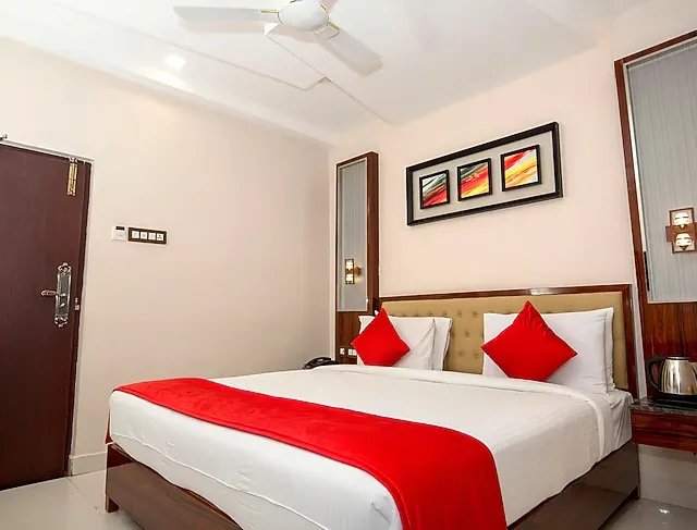 Deluxe room at Hotel President Madurai featuring larger bed, seating area, and warm lighting